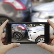 A person using their smartphone to take a picture of their car accident.